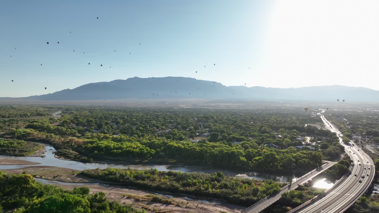 Vista dal drone di molteplici mongolfiere che volano sopra Albuquerque, Nuovo Messico, al mattino presto, vicino alle Montagne Sandia.