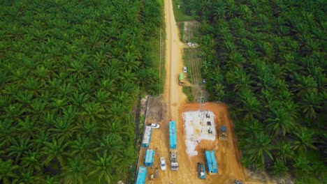 cinematic drone footage of onshore drilling rig equipment structure for oil exploration and exploitation in the middle of jungle surrounded by palm oil trees during sunset and high oil price