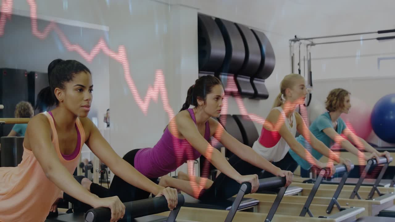 Four women pressing pilates reformers after coach cue for form, waveform with numeric readouts