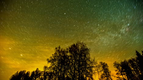 5k time lapse of beautiful milky way galaxy with rotating stars and colorful sky - silhouette of trees in foreground