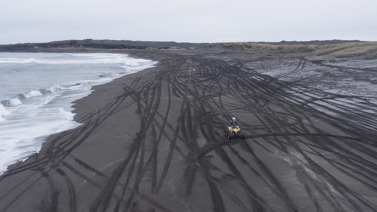 antena de paseos en quad en la playa de arena negra en islandia volcánica