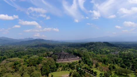 Iconic-Buddhist-temple-Borobudur,-Indonesia-surrounded-by-tropical-forest-aerial