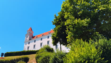 white façade of the beautiful bratislava castle. low angle view at the landmark surrounded by lush greenery