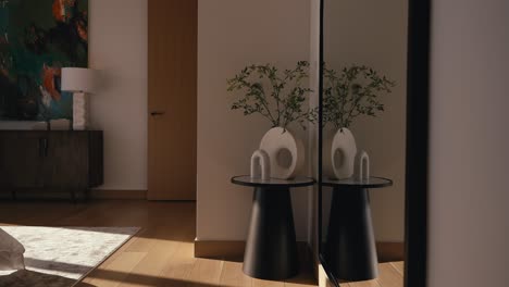 sun shades rising to reveal sunlight hitting a side table next to a mirror on the table is a plant with a modern vase