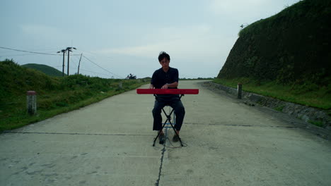 jugador de teclado sentado tocando su instrumento en una carretera de vehículos