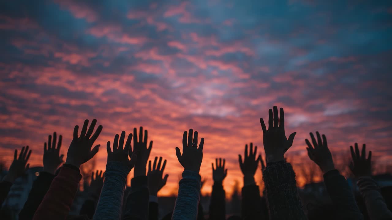 A Stunning Display of Unity Under a Colorful Sky: Raised Hands Emerge Against a Dramatic Sunset, Signifying Hope, Togetherness, and Collective Spirit