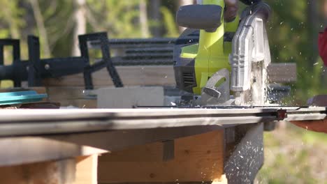 slow motion, pan shot, of a circular saw, circling through a plank, on a sunny summer day, in ostrobothnia, finland