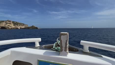 First-person-view-of-bow-of-sailboat-sailing-along-Bonifacio-Corse-cliffs-in-Corsica,-France