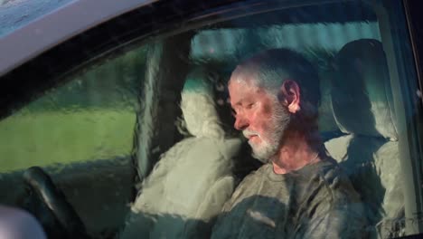 very sad man sitting in automobile dealing with depression as rain hits the windshield in slow motion