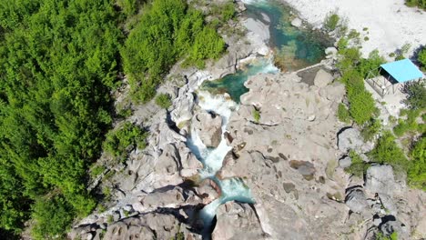 Drohnenansicht-In-Albanien-In-Den-Alpen,-Fliegende-Draufsicht,-Blaues-Kristallklares-Wasser,-Felsige-Seiten-Des-Flusses-Und-Grünes-Tal-In-Theth