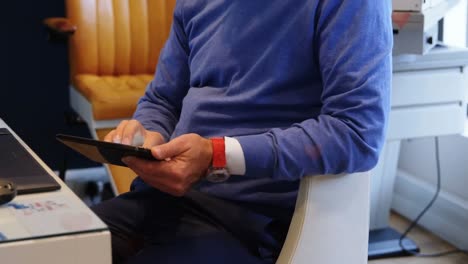 animation of social media heart icons over businessman using tablet