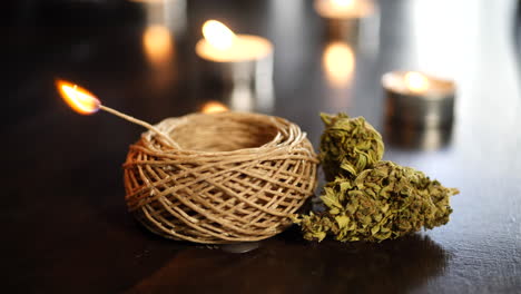 marijuana buds for medicinal and recreational smoking next to a hemp wick used to get high and candles in the backgound