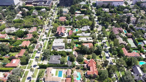 Drone-shot-flying-over-beautiful-West-Hollywood,-Los-Angeles,-California-neighborhood-filled-with-palm-tree-lined-streets,-cars,-mansions-and-swimming-pools