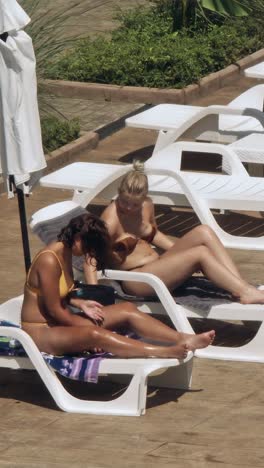 beautiful young women relaxing on the deck chair near the pool