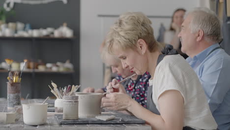 Three-elderly-people-work-on-a-potter's-wheel-in-slow-motion