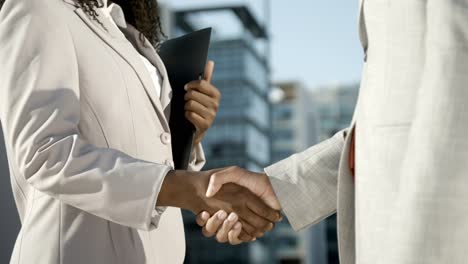 woman with folder shaking hands with colleague