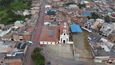 aerial footage of parroquia nuestra señora de los dolores surrounded by a bustling townscape. the vibrant urban scenery and historic architecture are captured under natural lighting