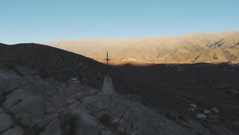 panoramic view of a mountainous landscape with a cross monument overlooking a valley town