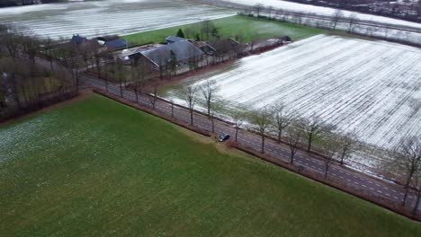 aerial view above agricultural fields covered in snow and farm buildings, winter landscape in the netherlands