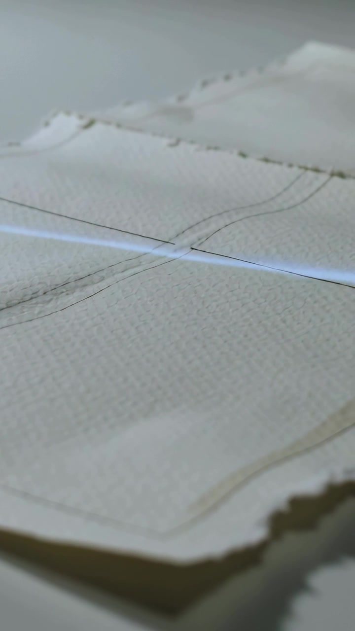 Video verticale: Luce in movimento che crea una striscia blu attraverso fogli perforati sulla scrivania, incrociando le linee.