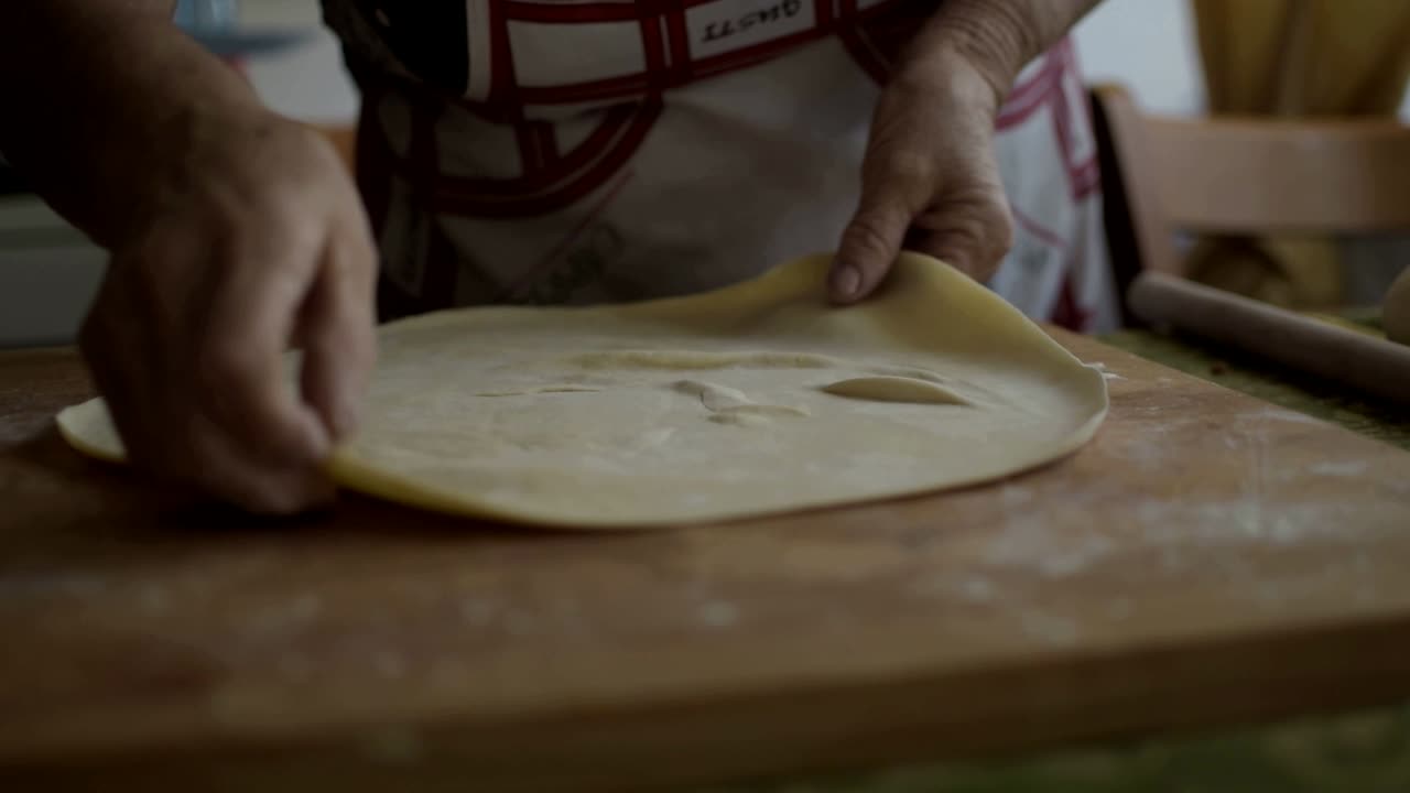 mujer italiana haciendo una hoja muy delgada de masa antes de cortar la pasta