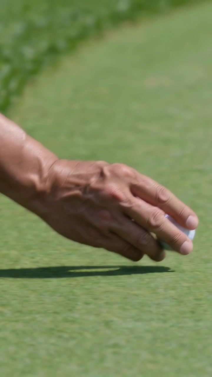 Video verticale: Golfista con guanto sul bordo del green, vede la pallina da golf, la raccoglie e la posiziona per il putt.