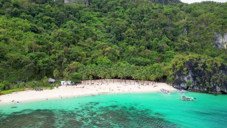 El-nido-Palawan-region-beach-with-coconut-palm-trees-and-paraw-canoe,-aerial-orbit