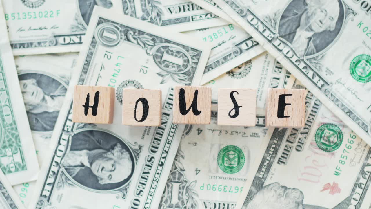 rotating word house from wooden letters, on dollars, concept
