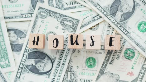 rotating word house from wooden letters, on dollars, concept
