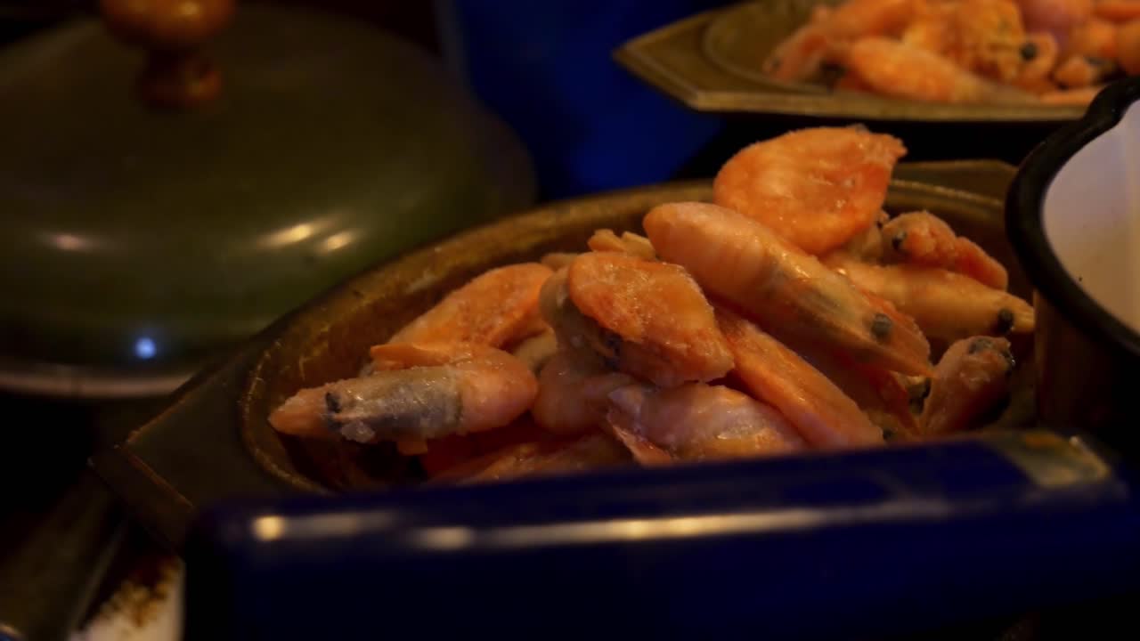 tiro manual de gambas congeladas en una olla pequeña para un plato cajún en la cocina del campo