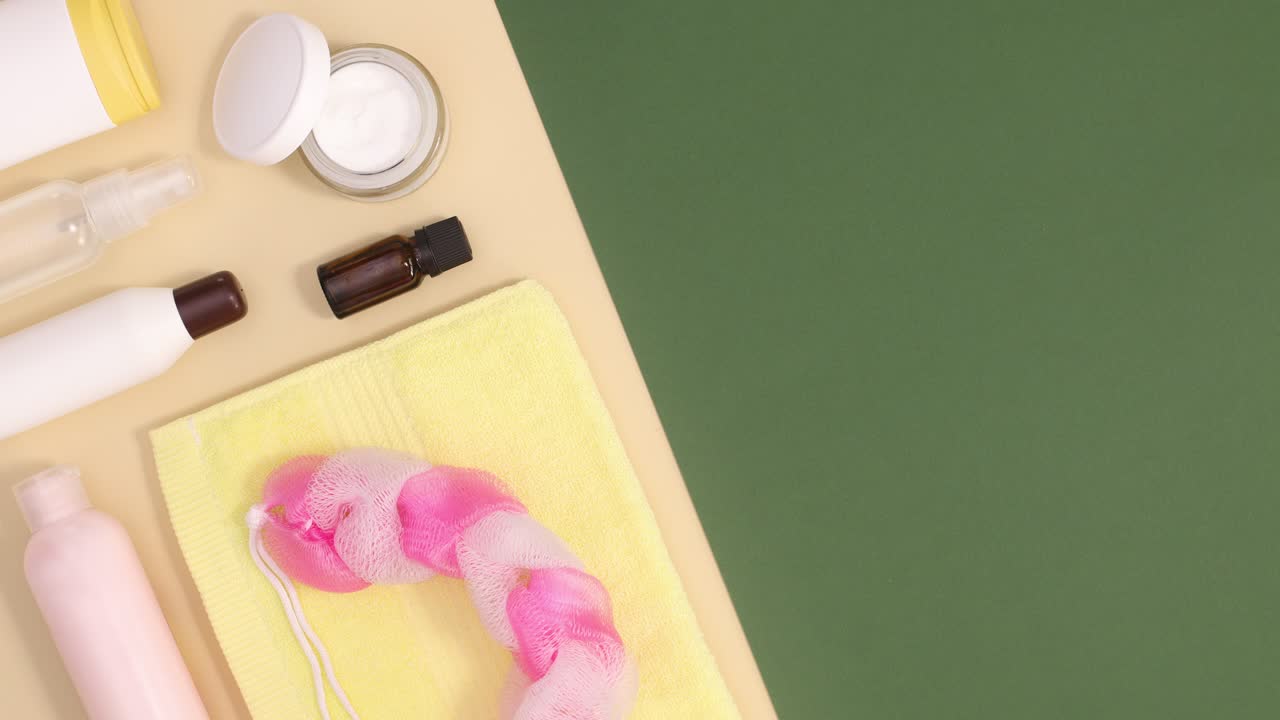 노란색 수건을 가진 스파 피부 관리 제품은 베이지색과 어두운 녹색 바탕에 움직입니다.