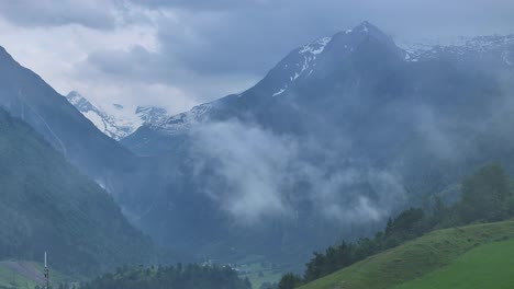 snowy peaks of alpine mountain range partially hidden by thick mist