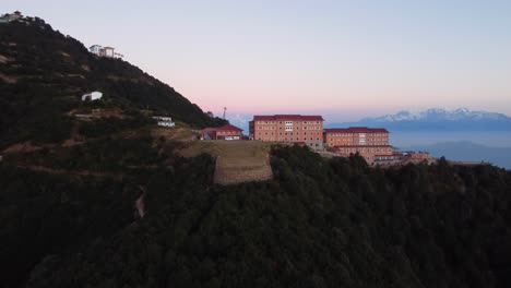 kathmandu, nepal - december 12, 2021: an aerial view of a resort perched on a hilltop with the himalayan mountain range in the background