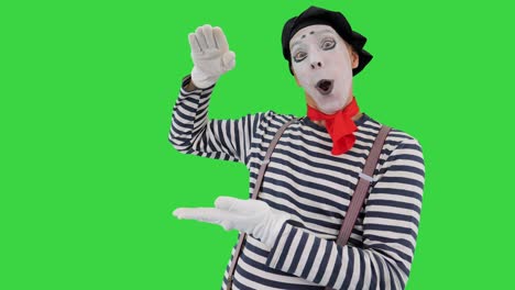 male mime artist performing showing growth, high interest rates, high income with his hands on a green screen, chroma key