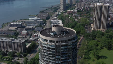 Una-Vista-De-Drones-De-Un-Edificio-Cilíndrico-Alto-En-El-Lado-De-Nueva-Jersey-Del-Río-Hudson-En-Un-Día-Soleado