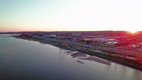 Puesta-De-Sol-Sobre-New-Haven,-Connecticut,-Con-Una-Vista-Aérea-Panorámica-De-La-Costa-Y-El-Paisaje-Urbano-Bañado-Por-Una-Luz-Dorada