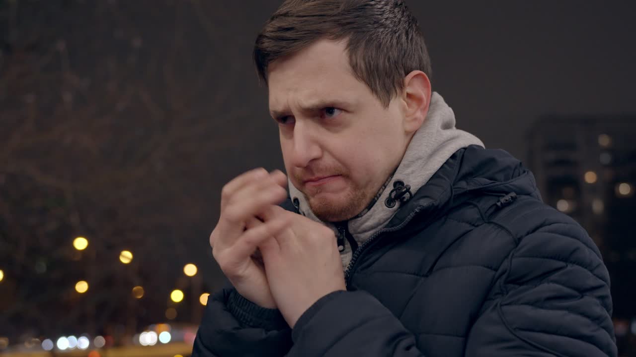 추운 겨울 저녁 야외에서 몸을 녹이기 위해 손을 비비며 몸을 녹이는 30대 남성