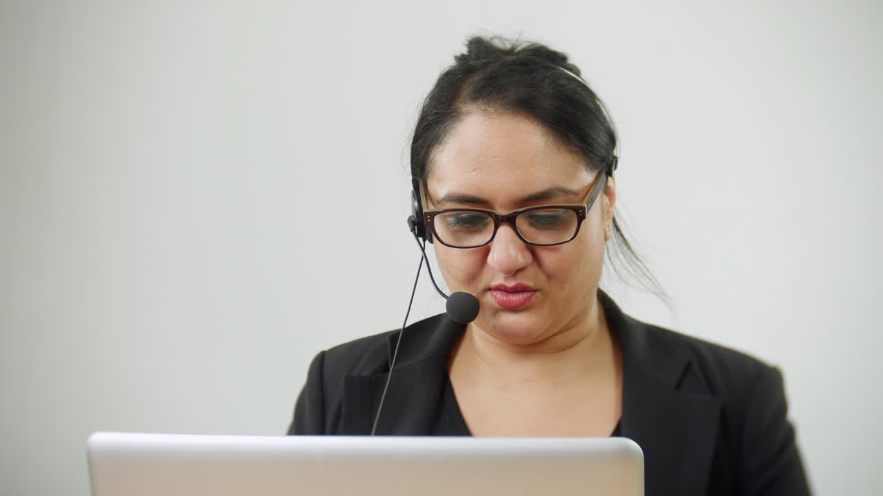 Un agente di viaggi in un call center sta prendendo una prenotazione al telefono mentre cerca i dati del cliente sul computer.