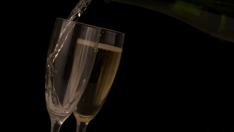 champagne pouring into flutes on black background