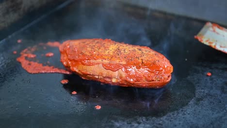 pan de hamburguesa siendo tostado con aceite de salsa de tomate en un restaurante