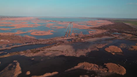 aerial view of salins de camargue's marshes and salt pans, with brown-toned islets and blue sky