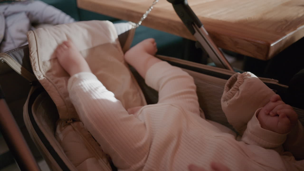 Close up of a baby's legs resting in a stroller near a table at a restaurant