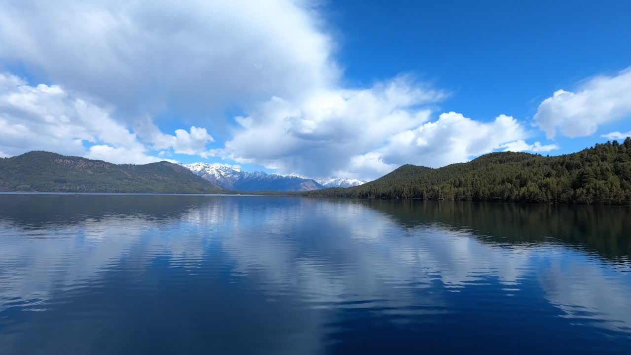 A calm aerial view of Rara Lake in Nepal shows its crystal-clear water surrounded by peaceful hills and Himalayan scenery, highlighting the beauty of this remote high-altitude destination