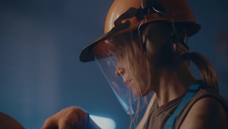 woman concentrated on woodworking task with safety gear