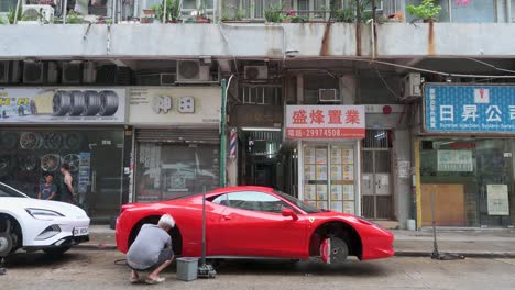 red ferrari having tire changed on busy hong kong street