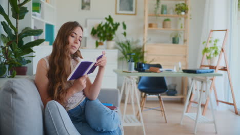 Smiling-Woman-Reading-While-Walking-Sitting-on-Sofa-at-Home