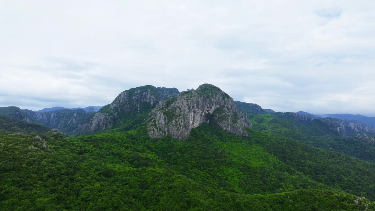 ภาพพาโนรามาโดรนเหนือเทือกเขาสีเขียว เผยให้เห็นยอดเขาหินปูนขรุขระที่สูงตระหง่านเหนือป่าฝนหนาทึบ