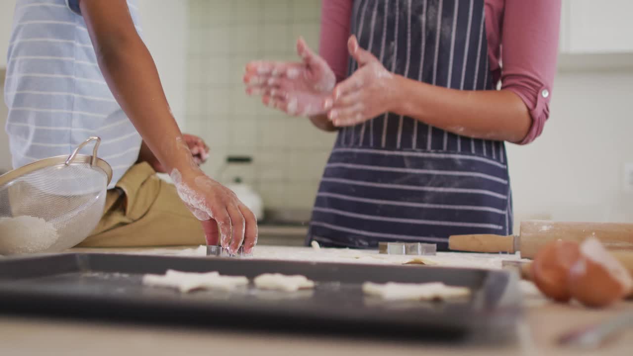 madre y hijo afroamericanos en la cocina cocinando, mirando la tableta