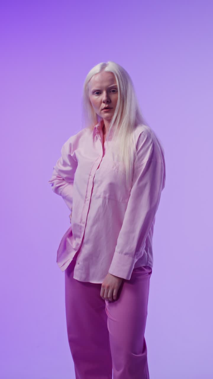 Kvinne med blondt hår i rosa skjorte som poserer