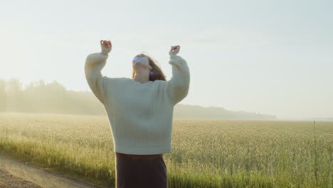 woman dancing in a wheat field at sunrise